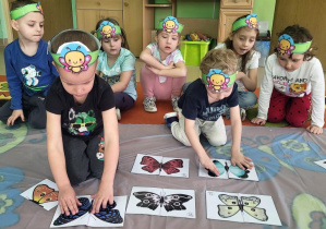 Chłopcy składają motyle biorąc pod uwagę oś symetrii.