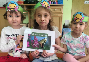 Dziewczynki prezentują ilustrację przedstawiającą budowę motyla.