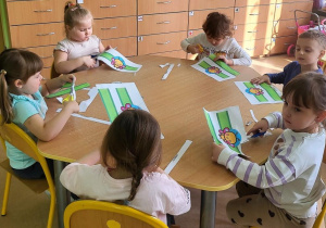 Dzieci wycinają opaski z emblematem motyla.