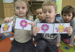 Dzieci prezentują kształty dobrane w pary ukryte na motylkach i kwiatkach.