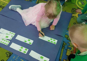 Dziewczynka przelicza żabki i wpisuje odpowiednią cyfrę