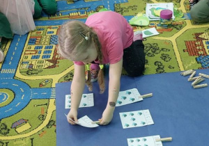 Dziewczynka ptrzelicza muchy i spinaczem zaznacza odpowiednią cyfrę