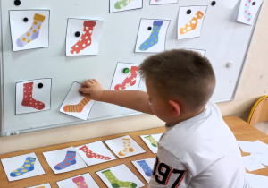 Chłopiec zdejmuje skarpetkę zgodnie z usłyszaną instrukcją