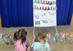 Dziewczynki wieszają skarpetki na sznurku za pomocą klamerek.