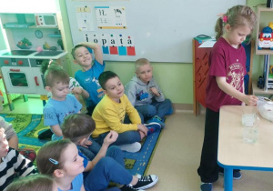 Dziewczynka wsypuje sól do szklanki w wodą