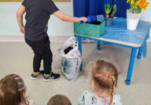 Chłopiec wsypuje ziemię do doniczki.