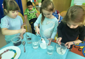 Dziewczynki badają rozpuszczanie substancji w wodzie.