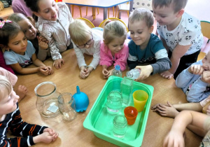 Chłopiec przelewa wodę z butelki do pojemnika