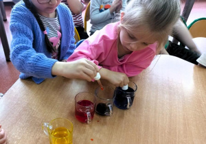 Dziewczynki mieszają dwa kolory zabarwionej wody