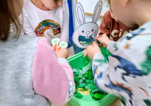 Dzieci dokarmiają papierowego króliczka.