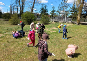 Dzieci sprzatają teren szkoły.