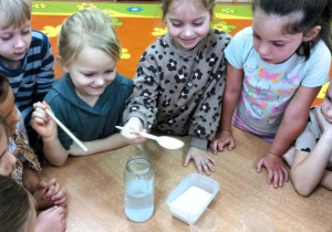Dziewczynki rozpuszczają sól do eksperymentu.