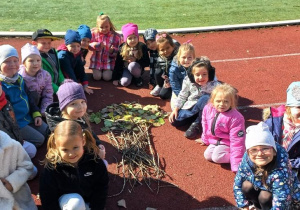 Pamiątkowe zdjęcie przy drzewie zrobionym z gałązek i liści.