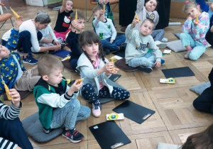 Dzieci prezentują świece wykonane z wosku.