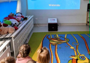 Dzieci oglądają film edukacyjny o morskich stworzeniach.