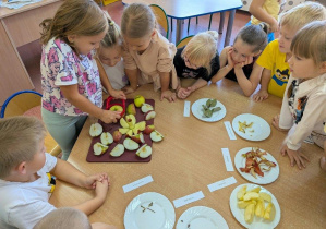 Dziewczynka próbuje podzielić jabłko na kawałki.
