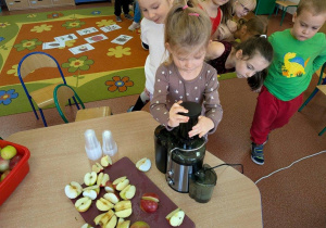 Dziewczynka robi sok z jabłek.