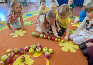 Dziewczynki układają jabłka od największego do najmniejszego.