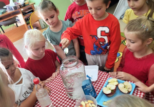 Chłopiec wsypuje sodę oczyszczoną do słoika z wodą.