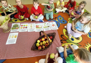 Dzieci rozwiązują zagadki i słuchają ciekawostek o jabłkach.