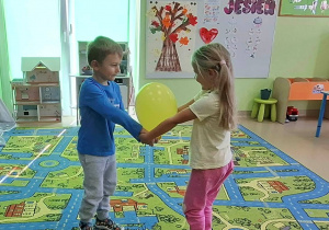 Dzieci w parach przenoszą balon.