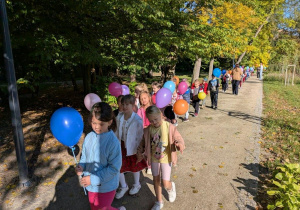 Przedszkolaki maszerują z balonami.