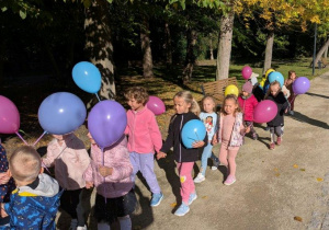 Przedszkolaki maszerują z balonami.