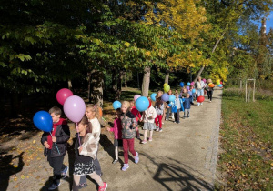 Przedszkolaki maszerują z balonami.