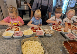Dziewczynki komponują swoją pizzę.