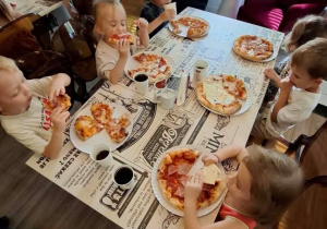 Dzieci degustują przygotowaną pizzę.