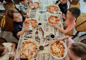 Dzieci degustują przygotowaną pizzę.