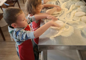 Dzieci przygotowują spody do pizzy.