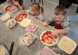 Dzieci układają składniki na pizzy.