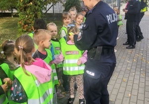 Pani policjantka rozdaje dzieciom odblaski.