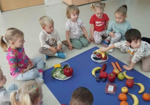 Chłopiec wkłada owoc na odpowiedni talerzyk.