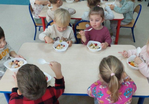Dzieci degustują sałatkę owocową.
