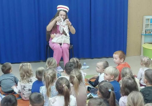 Pielęgniarka prezentuje małe ubranko dla dzidziusia.
