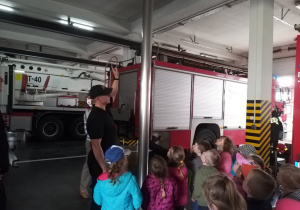 Dzieci oglądają rurę po której zjeżdżają strażacy.