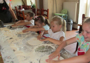 Dzieci przygotowują ciasto na pizzę.