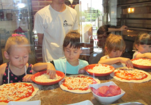Dzieci wybierają dodatki do pizzy.