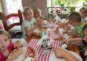 Dzieci jedzą pizzę.