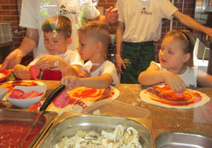 Dzieci wybierają dodatki do pizzy.