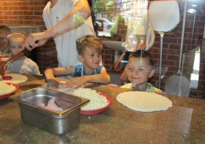 Dzieci przygotowują ciasto na pizzę.