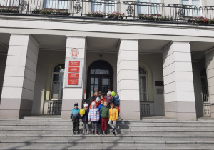 Dzieci z grupy Motylki stoją na schodach przed Urzędem Miasta