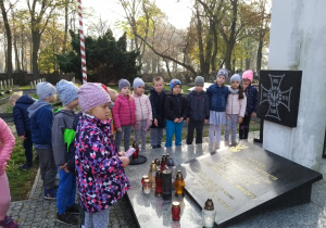 Dzieci stoją pod pomnikiem pomordowanych w Katyniu.